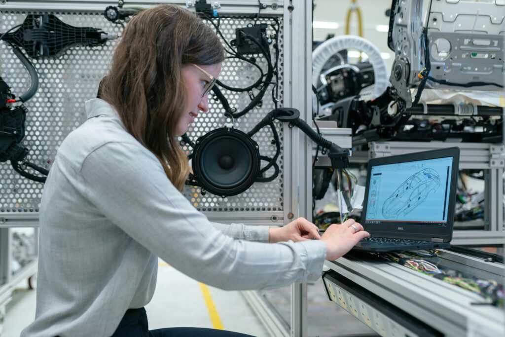 Woman conducting engineering research in a sound system workshop using a laptop.